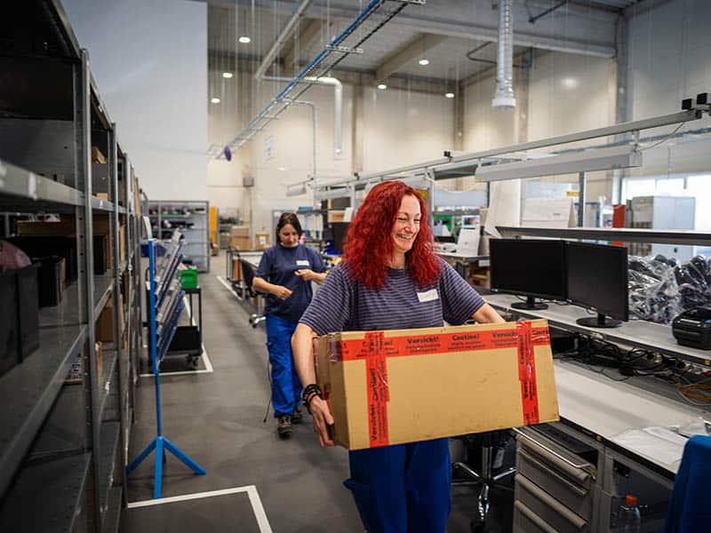 Cattron employee in warehouse carrying a box