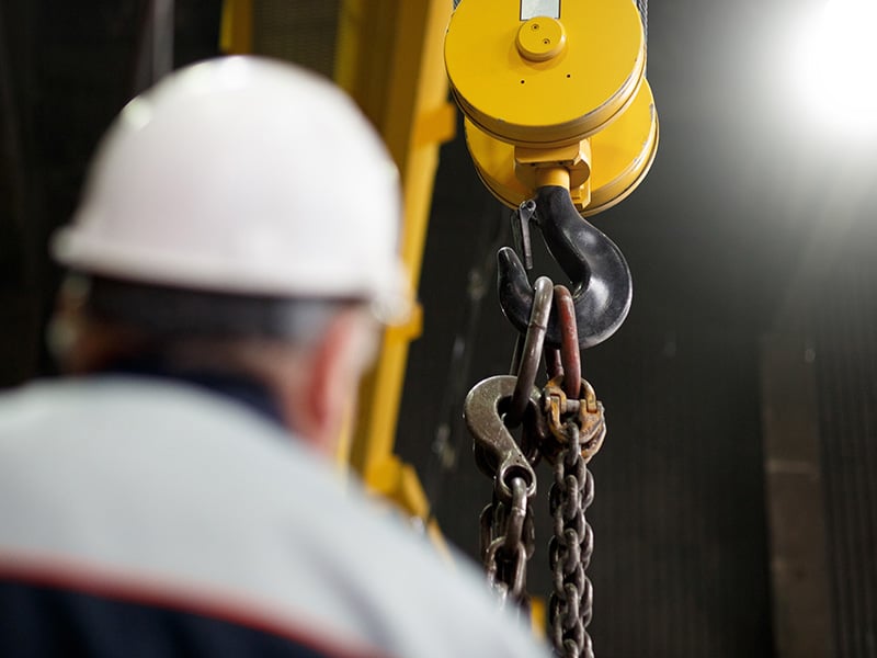 Worker in a white hard hat in front of an industrial hook