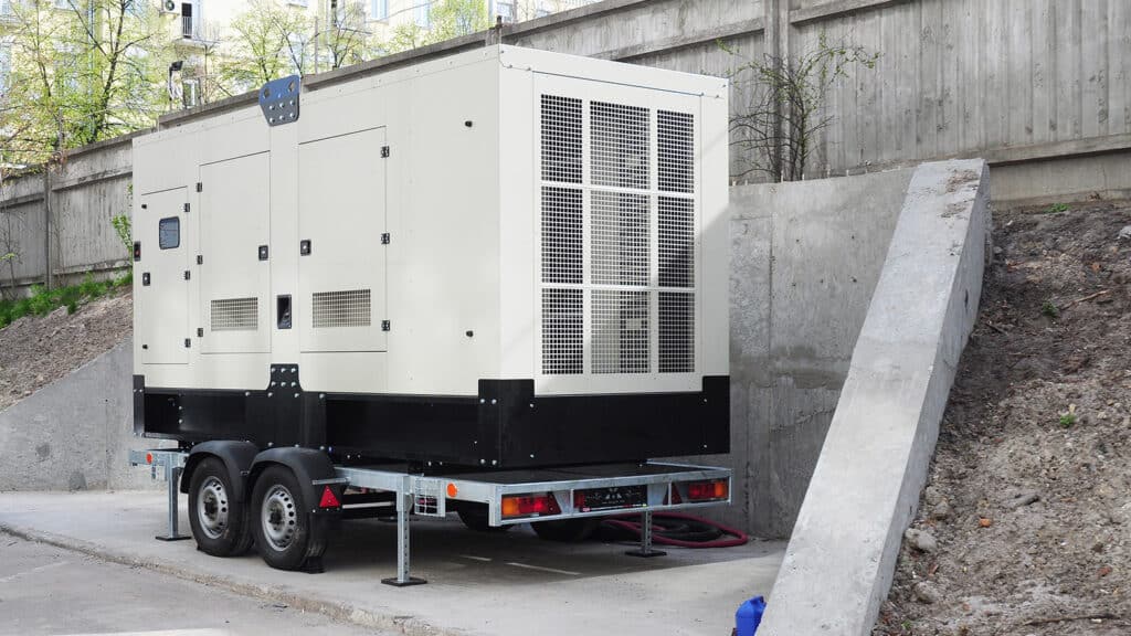 large white mobile generator sitting next to a retaining wall